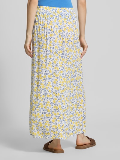 Frauenmodel trägt Maxi-Rock aus reiner Viskose Modell 'BARRI' von Pieces, Optik:Allover-Muster, schmale Passform, Maxi-Länge, Bundabschluss: Elastisch, Material: Viskose, gelb-weiß-blaues Blattmuster, glatte Struktur, Ganzkörperansicht Rückansicht.