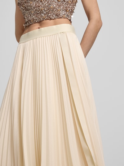 Frauenmodel trägt Plisseerock mit elastischem Bund von V by Vera Mont aus cremefarbenem Chiffon in A-Linie, Nahaufnahme Oberkörper.
