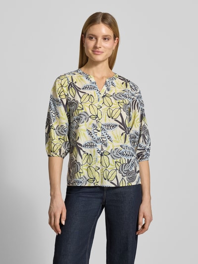 Frauenmodel trägt Regular Fit Bluse mit floralem Allover-Print von Soyaconcept aus reiner Baumwolle, Tunika-Ausschnitt, Knopfleiste, Rückenlänge 64 cm, Ärmellänge 45 cm, helle Farben, lockere Form, Nahaufnahme Oberkörper.