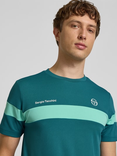 Männermodel trägt Regular Fit T-Shirt mit Logo-Print Modell 'Leone' von SERGIO TACCHINI, grüne Farbtöne, Nahaufnahme Oberkörper, Herren T-Shirt, Rundhalsausschnitt, Rückenlänge bei Größe M: 71 cm.