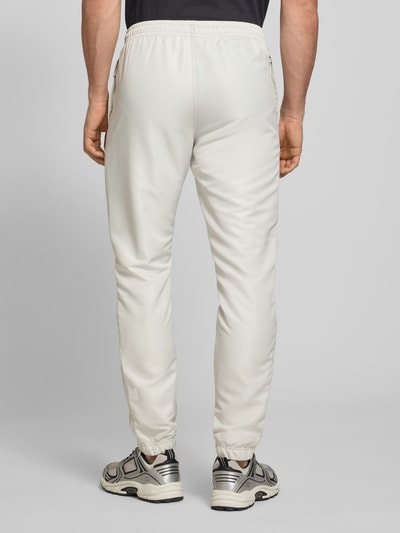 Männermodel trägt Regular Fit Tracksuit mit Logo-Stitching Modell 'Carson' von SERGIO TACCHINI in Weiß, elastische Abschlüsse, Ganzkörperansicht Rückansicht.
