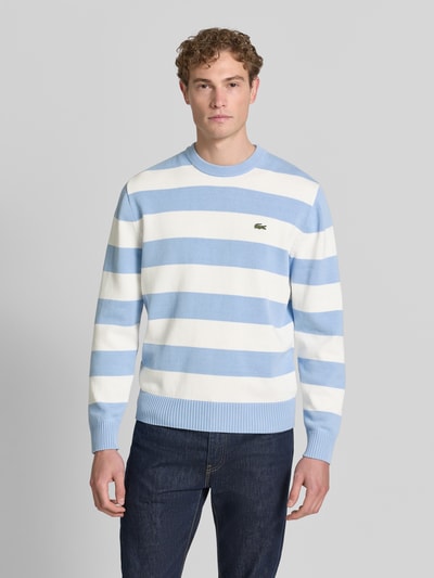 Männermodel trägt Regular Fit Pullover aus reiner Baumwolle von Lacoste mit Optik:Allover-Muster, Label-Patch, Ganzkörperansicht von vorne.