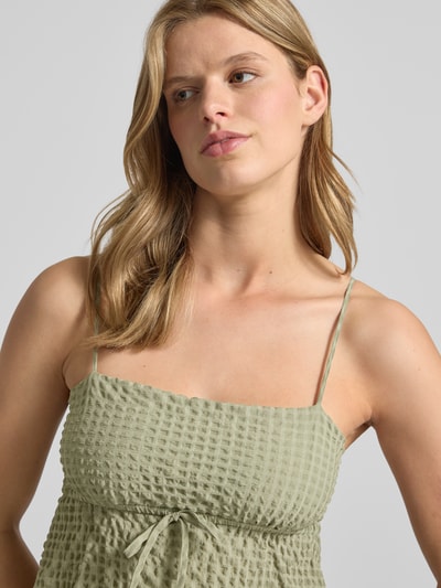Frauenmodel trägt Babydoll-Top aus Seersucker mit Schnürung von REVIEW in hellem Grün, Strukturmuster, Material-Mix mit Stretch-Anteil, Nahaufnahme Oberkörper.