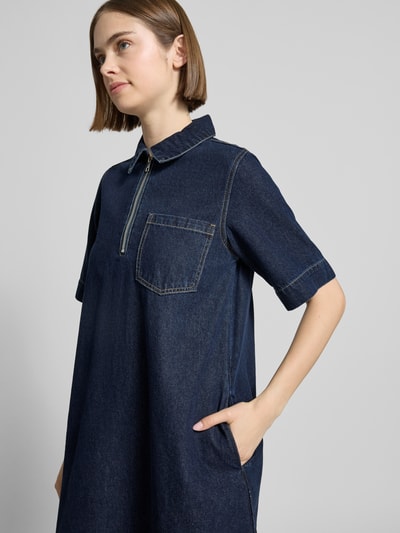 Frauenmodel trägt Jeanskleid mit Reißverschluss Modell 'AMARA KLARA' von JJXX aus Baumwoll-Viskose-Mix, A-Linie, Hemdblusenkragen, Brusttasche, dunkles Blau, Minikleid, Nahaufnahme Oberkörper.