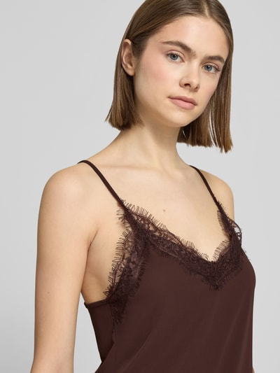 Frauenmodel trägt Regular Fit Top mit Spitzenbesatz von Gina Tricot in Dunkelbraun mit V-Ausschnitt und Spaghetti-Trägern, Nahaufnahme Oberkörper.