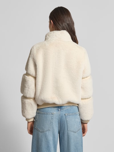 Frauenmodel trägt Jacke mit Teddyfell und gerippten Abschlüssen von Guess, cremefarben, gerader Schnitt, Ganzkörperansicht Rückansicht. Rückenlänge bei Größe S: 56 cm, Schulterbreite: 38 cm, Brustweite: 53 cm, Ärmellänge: 61 cm.