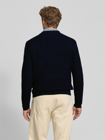 Männermodel trägt Regular Fit Pullover aus Baumwoll-Woll-Mix von GANT in Dunkelblau, cremefarbene Hose, Ganzkörperansicht Rückansicht.