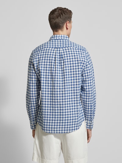 Męski model nosi Regular Fit Leinenhemd mit Baumwoll-Anteil Modell 'GINGHAM' od Gant, niebiesko-biała krata, długi rękaw, zaokrąglony dół, szew z logo, bawełniano-lniana mieszanka, krój regular fit, widok całej sylwetki z tyłu.