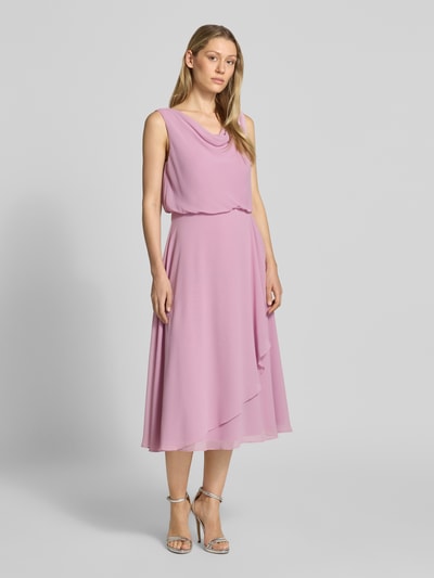 Modelka nosi knielanges Cocktailkleid mit Wasserfall-Ausschnitt von Christian Berg Cocktail z szyfonu, taliowany fason, długość do kolan, szerokie ramiączka, dół w kopertowym stylu, zapięcie na haftkę i zamek błyskawiczny z tyłu, długość tyłu w rozmiarze 36: 120 cm, szerokość klatki piersiowej w rozmiarze 36: 45 cm, jasnoróżowy kolor, miękka faktura, gładka powierzchnia, widok całościowy z przodu.