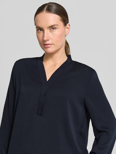 Frauenmodel trägt Bluse mit V-Ausschnitt und Label-Detail von Marc Cain in Dunkelblau, Damen Loose-Fit, Nahaufnahme Oberkörper. Rückenlänge bei Größe 36: 46 cm, Ärmellänge bei Größe 36: 60 cm, elastische Ärmelabschlüsse.