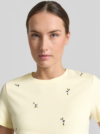 Frauenmodel trägt Regular Fit T-Shirt mit floralem Allover-Stitching Modell 'Flowi' von Mango aus Reine Baumwolle, Rundhalsausschnitt, Kurzärmelig, Florales-Allover-Muster, Rückenlänge bei Größe S 55 cm, Nahaufnahme Oberkörper.