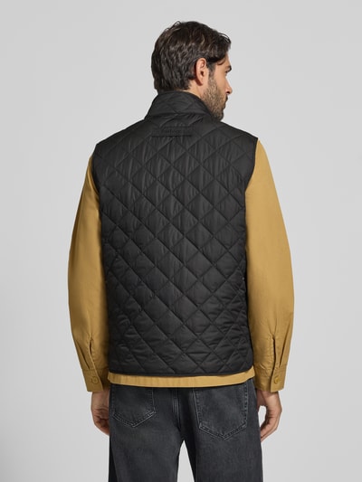 Männermodel trägt schwarze, gesteppte Slim Fit Weste mit Logo-Stitching Modell 'NEW LOWERDALE' von Barbour, Herren Weste, Ganzkörperansicht Rückansicht.
