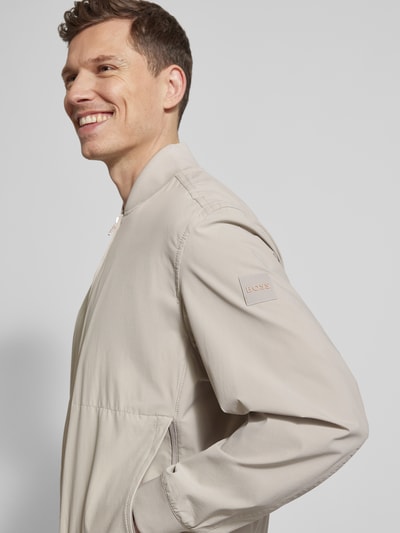 Männermodel trägt Regular Fit Blouson mit Baseball-Kragen Modell 'OSURF' von BOSS Orange in Unifarbe mit Reißverschluss, Nahaufnahme Oberkörper.