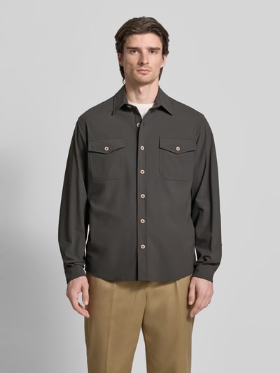 Männermodel trägt Hemdjacke mit Knopfleiste von CRUNA in Dunkelgrau, Material-Mix mit Stretch, Brusttaschen, Ganzkörperansicht von vorne.