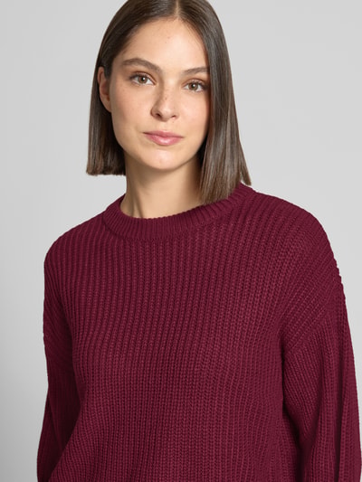 Frauenmodel trägt Regular Fit Pullover mit Crew Neck Modell 'LEA' von VERO MODA in dunklem Bordeauxrot mit grober Strickstruktur, Nahaufnahme Oberkörper.