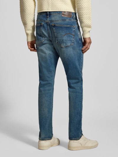 Männermodel trägt Regular Tapered Fit Jeans im Used Look Modell '3301' von G-Star aus Baumwoll-Elasthan-Mix, Eingrifftaschen, Ganzkörperansicht Rückansicht.