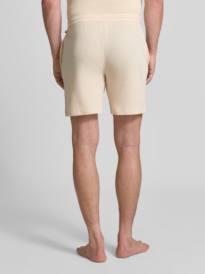Männermodel trägt Regular Fit Sweatshorts aus Baumwoll-Mix von BOSS in Beige, glatte Struktur, Ganzkörperansicht Rückansicht. Herren Sweatshorts von BOSS.