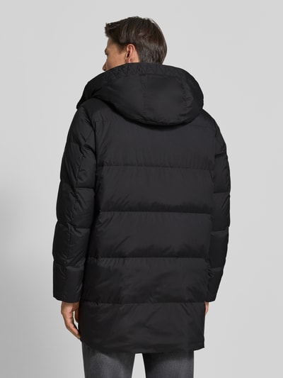 Männermodel trägt Regular Fit Daunenjacke mit Kapuze von Marc O'Polo, unifarben schwarz, Steppstruktur, wasserabweisend, Ganzkörperansicht Rückansicht.