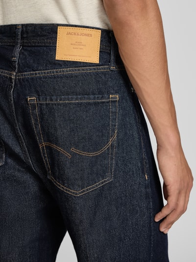 Männermodel trägt Wide Fit Jeans aus reiner Baumwolle Modell 'Alex' von JACK & JONES, dunkles Denim, sichtbare Ziernähte, Nahaufnahme Rückansicht.