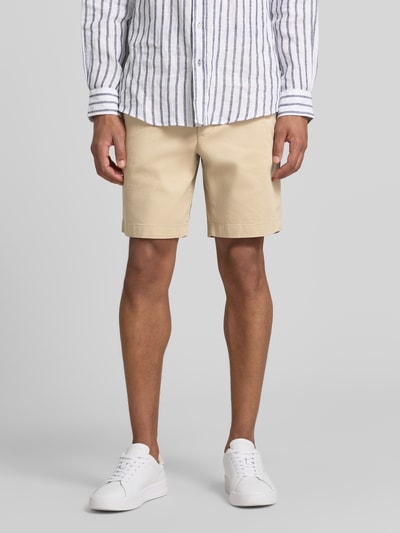Männermodel trägt Chinoshorts aus Baumwoll-Mix Modell 'DOVER' von Tommy Hilfiger, Optik: Unifarben, Passform: Regular-Fit, Verschluss: Knopf und Reißverschluss, seitliche Eingrifftaschen, Paspeltaschen mit Knopf, Material: Baumwoll-Mix, helle Beige-Töne, glatte Struktur, Ganzkörperansicht von vorne.