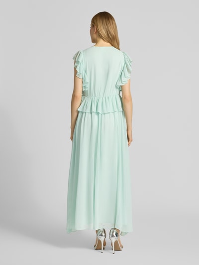 Frauenmodel trägt Cocktailkleid mit Volants Modell 'MUSSI' von YAS in Hellgrün, fließender Stoff, Gerader-Schnitt, Midikleid, Ganzkörperansicht Rückansicht.