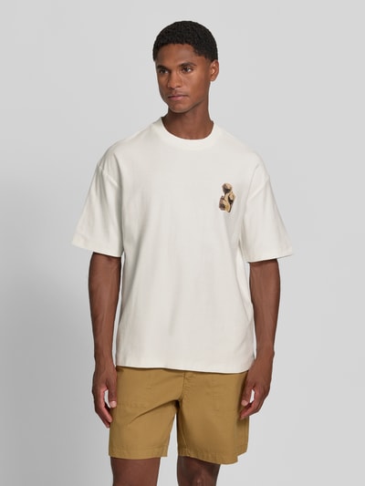 Männermodel trägt Regular Fit T-Shirt aus reiner Baumwolle Modell 'Detzi' von HUGO, cremeweiß, dezente Verzierung, lockere Form, Herren T-Shirt, Ganzkörperansicht von vorne.
