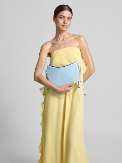 Frauenmodel trägt Handtasche aus Leder mit Label-Detail von FURLA in Hellblau mit Schulterriemen und Magnetverschluss, Nahaufnahme Oberkörper. Hauptfach, Maße: Breite 29 cm, Länge 26 cm, Tiefe 3 cm, Schulterriemen 40 cm.