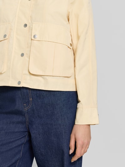 Vrouwenmodel draagt Jacke mit Stehkragen und Pattentaschen van Fuchs Schmitt in regular fit, lichte kleur, met grote klepzakken, knoopsluiting, tunnelkoord, detailopname bovenlichaam.
