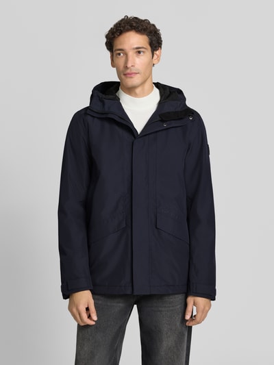Männermodel trägt Regular Fit Jacke mit Kapuze Modell 'Adam' von Didriksons in Dunkelblau, Eingrifftaschen, Ganzkörperansicht von vorne. Rückenlänge 79 cm, Schulterbreite 46 cm, Brustweite 58 cm, Ärmellänge 73 cm.