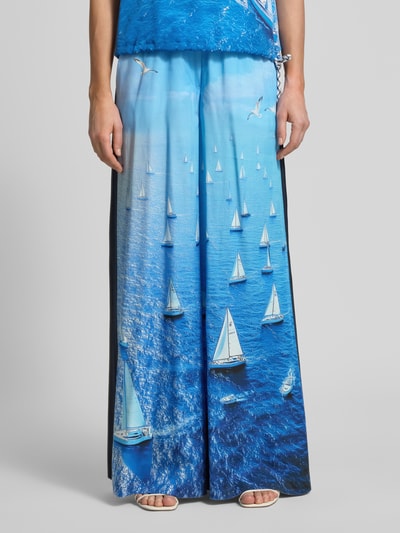 Frauenmodel trägt Wide Fit Stoffhose aus reinem Lyocell von Marc Cain mit Allover-Motiv-Print in Ozeanblau, elastischer Bund, Nahaufnahme Oberkörper.