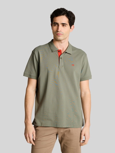 Męski model nosi Regular Fit Poloshirt aus reiner Baumwolle od Tom Tailor, oliwkowy, gładki, logo, bawełna piké, krój regular fit, widok z przodu, całe ciało.