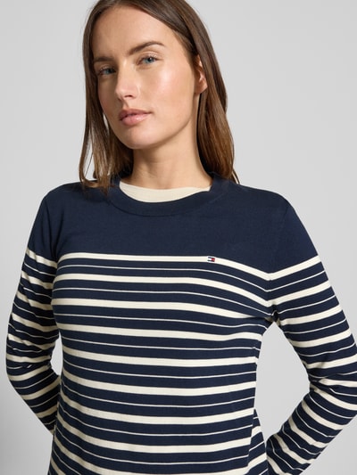 Vrouwenmodel draagt Regular Fit Strickpullover aus Baumwoll-Mix van Tommy Hilfiger, gestreept, marineblauw-crèmekleurig, ribgebreid, logo-stiksel, lange mouw, crew neck, Nahaufnahme bovenlichaam.