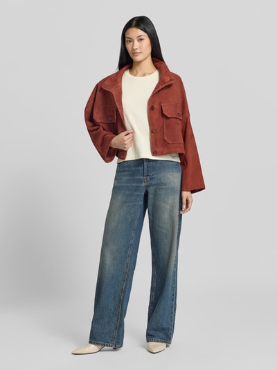 Frauenmodel trägt Boxy Fit Strickshirt aus Viskose-Mix Modell 'VMSILJE' von VERO MODA in Creme, kombiniert mit Jeans, Ganzkörperansicht von vorne.