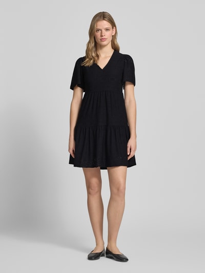 Kobiece model prezentuje Mini-Freizeitkleid mit Lochstickmuster Modell 'SMILLA LIFE' od Only, czarny, krój regular fit, mini, V-dekolt, krótki rękaw, jednolity, detaliczne przeszycia, struktura ażurowa, całkowity wygląd z przodu.
