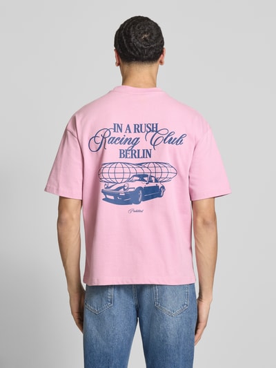 Männermodel trägt Regular Fit T-Shirt aus reiner Baumwolle Modell 'IN A RUSH' von PROHIBITED in Rosa mit blauem Print, Ganzkörperansicht Rückansicht.