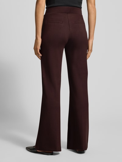 Frauenmodel trägt Flared Cut Hose mit elastischem Bund von Christian Berg Woman in Dunkelbraun, glatte Textur, Gesäßtaschen, Material-Mix mit Viskose-Anteil, Ganzkörperansicht Rückansicht.