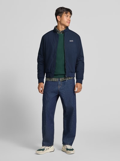 Männermodel trägt donkerblauwe bomberjack met opstaande kraag van JACK & JONES, Logo, ritssluiting, regular fit, model 'BROOKLYN', heren, Ruglengte maat M 67 cm, schouderbreedte 49 cm, borstwijdte 59 cm, mouwlengte 66 cm, Ganzkörperansicht von vorne.