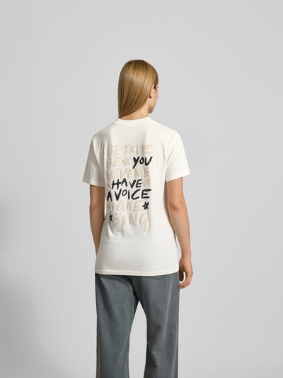 Frauenmodel trägt T-Shirt mit Label-Print von Anine Bing aus reiner Baumwolle, lockerer Schnitt, Rückenlänge 70 cm, Ganzkörperansicht Rückansicht.
