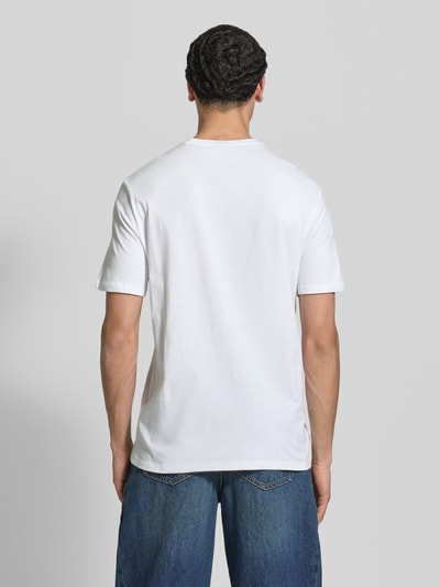 Männermodel trägt T-Shirt mit Label-Patch Modell 'BADGE' im 2er-Pack von Calvin Klein Jeans, weiße Baumwolle, gerader Schnitt, Ganzkörperansicht Rückansicht.