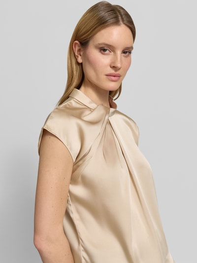Frauenmodel trägt Blusenshirt aus Satin Modell 'Fleur' von Neo Noir in Beige mit Drapierung, Regular-Fit, Rundhalsausschnitt, Rückenlänge bei Größe 36: 58 cm, Nahaufnahme Oberkörper.