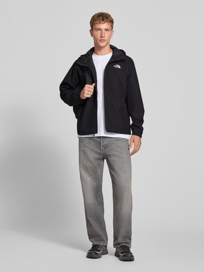 Männermodel trägt Regular Fit Jacke mit Logo-Print Modell 'Quest' von The North Face in Schwarz, Reißverschluss, Kapuze, Ganzkörperansicht von vorne. Kontext: Damen Jacke, Rückenlänge 100 cm, Schulterbreite 46 cm, Brustweite 58 cm, Ärmellänge 68 cm.