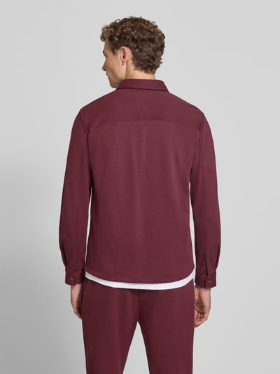 Männermodel trägt Overshirt mit Knopfleiste von MCNEAL in dunklem Rot, Material-Mix, gerader Schnitt, Brusttaschen, Rückansicht, Ganzkörperansicht.