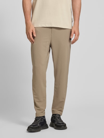Männermodel trägt Tapered Fit Hose mit Waffelstrukturmuster Modell 'TERRACE' von BOSS Green in Beige, Seiten- und Vorderansicht, Nahaufnahme Unterkörper. Moderne Herren Hose mit Allover-Waffelmuster, elastischem Bund mit Tunnelzug und seitlichen Eingrifftaschen.