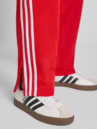 Männermodel trägt Sweatpants mit elastischem Bund von adidas Originals, lockerer Schnitt, Reißverschlusstaschen, Ganzkörperansicht von vorne