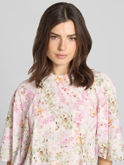 Modelka kobieca nosi Blusenshirt aus Viskose Modell 'Brina' od JOOP!, kolor jasnoróżowy z kwiatowym wzorem, luźny krój, stójka, rękaw 3/4, miękka tekstura, widoczna długość pleców 60 cm i długość rękawa 37 cm dla rozmiaru 36, zbliżenie na górną część ciała