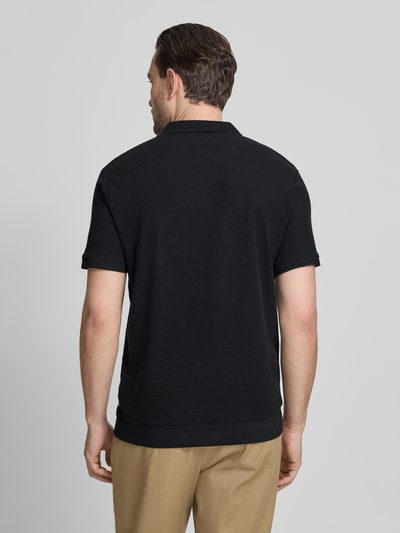 Männermodel trägt Comfort Fit Poloshirt mit V-Ausschnitt von Lindbergh in Schwarz mit Strukturmuster aus Reine Baumwolle, Label-Detail, Rückenlänge 68 cm bei Größe M, Ganzkörperansicht Rückansicht.