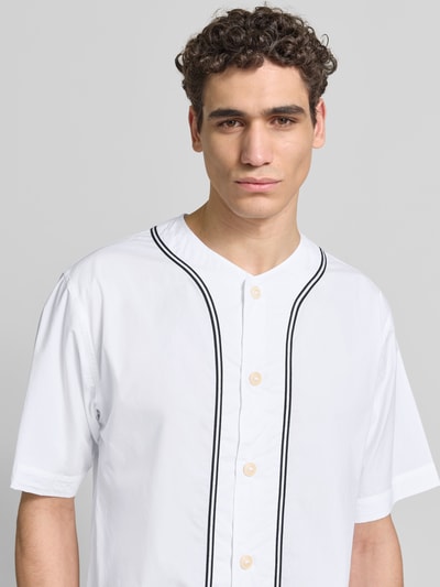 Männermodel trägt Freizeithemd in kurzärmeligem Design von Kenzo aus reiner Baumwolle, Relaxed-Fit, Rundhalsausschnitt, Knopfleiste, weiß mit schwarzen Linien, Nahaufnahme Oberkörper.