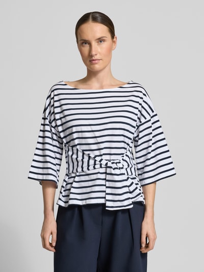 Frauenmodel trägt T-Shirt mit Knotendetail Modell 'DAJANA' von GUIDO MARIA KRETSCHMER WOMAN, Reine Baumwolle, taillierter Schnitt, Rundhalsausschnitt, 3/4-Arm, marine-weiß gestreift, Ganzkörperansicht von vorne.