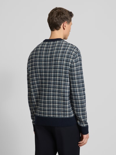 Männermodel draagt Regular Fit Strickpullover aus Woll-Mix Modell 'MIKOLAS' van SELECTED HOMME met all-over geruit patroon, lange mouwen, geribde boorden, kleurenmix van blauw en grijs, gebreide textuur, Ganzkörperansicht Rückansicht.
