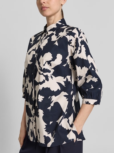 Vrouwenmodel draagt Bluse mit 3/4-Arm und verdeckter Knopfleiste van comma, katoenmix met stretch, straight fit, overhemdkraag, marineblauw met crèmekleurig bloemmotief, detailopname voorkant.